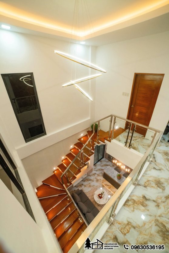 Double height stair void with a stainless and glass balustrade seen from the upper landing